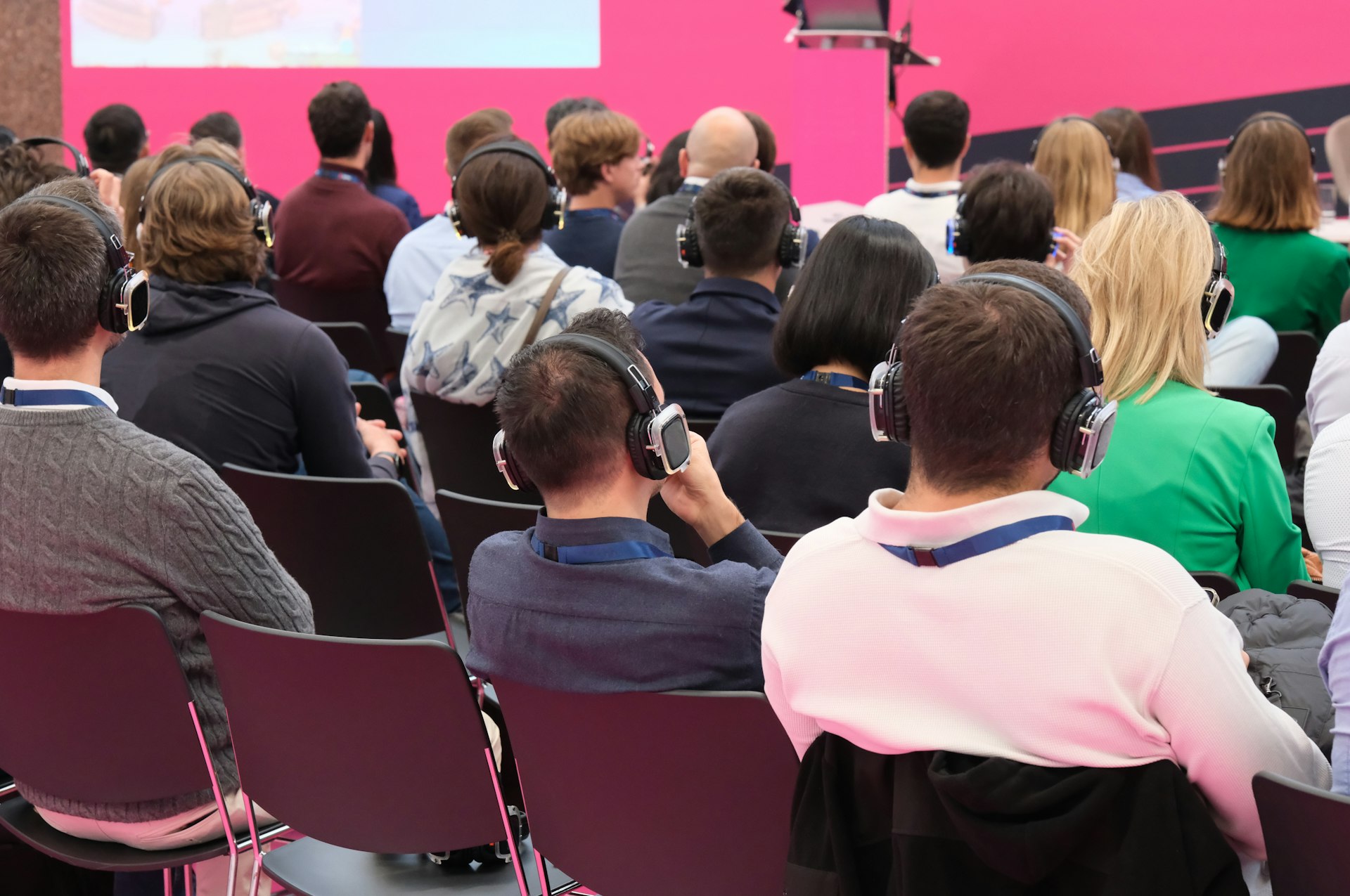 A group of people sitting in front of a pink wall